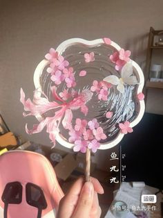 a person holding up a pink flower shaped lollipop