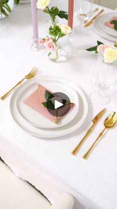 a table set with place settings, flowers and gold utensils for an elegant dinner