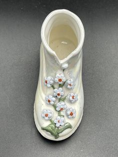 a ceramic vase with flowers painted on it's side and the bottom half is white