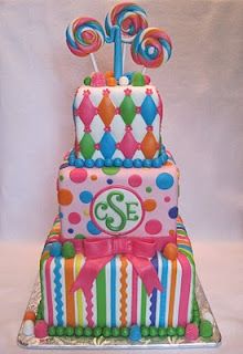 a three tiered cake decorated with candy and lollipops