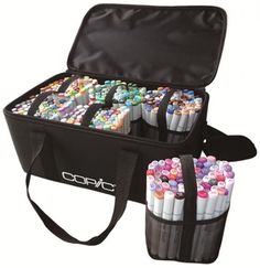 an open case filled with markers and pencils on top of a white table next to a black bag