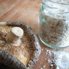 a jar filled with white stuff sitting on top of a wooden table next to a mushroom