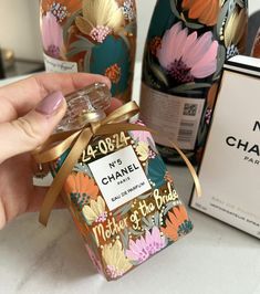 a hand holding a bottle of chanel no 4 perfume in front of two bottles