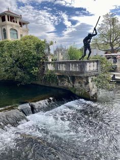 a statue is standing on the edge of a bridge over a river with water running under it