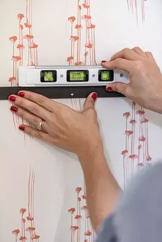 a woman is using an electronic device to measure wallpaper