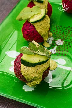 strawberries and avocado are arranged on a green platter with leafy garnishes