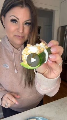 a woman is holding an avocado in her hand and pointing it at the camera