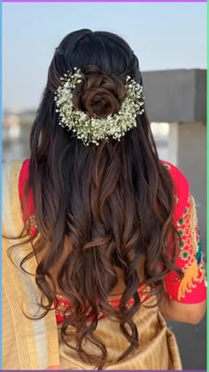 the back of a woman's head with long hair and flowers in her hair