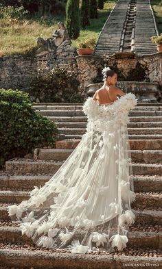 a woman is standing on some steps wearing a dress made out of flowers and feathers