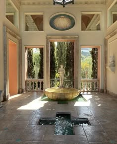 an indoor fountain in the middle of a room with large windows and doors leading to another area