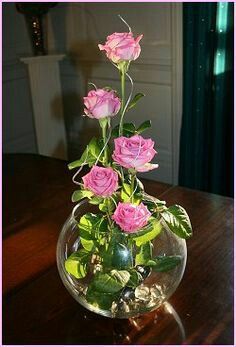 a vase filled with pink roses on top of a wooden table