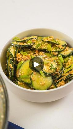 a white bowl filled with cooked zucchini on top of a blue and white table