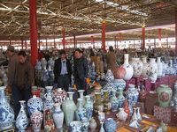 many different vases are on display in a large room with people looking at them