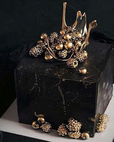 a gold crown on top of a black box with golden balls and chains around it