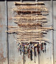 a group of sticks hanging from the side of a wooden wall with beads attached to them