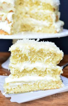 a piece of cake with white frosting on two plates next to each other and a fork in front of it