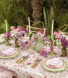 the table is set with pink and white flowers in vases, plates, utensils and napkins