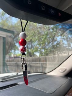 a red and white beaded car charm hanging from the dashboard