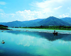 a man on a boat in the middle of a river with mountains in the background