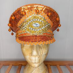 A stunning orange and gold sequinned festival hat with delicate trims and embellisments which will really ensure you stand out from the crowd. The hat is a size large/58cm but can be made to fit smaller sizes by adding padding to the inside band. At the back, there is a band of elastic which secures the hat and makes it comfortable to wear.  This piece would be a fantastic addition to your festival wardrobe, party outfit, or fancy dress costume. Perfect for adding a bit of sparkle to your pumpki Traditional Carnival Costume Hats And Headpieces For Party, Traditional Gold Costume Hats For Party, High Crown Gold Headpiece For Festival, Gold High Crown Headpiece For Festivals, Adjustable Costume Hats And Headpieces For Festivals, Bohemian Costume Hats And Headpieces For Festival Party, Bohemian Cap Costume Hats And Headpieces For Party, Bohemian Costume Hats And Headpieces For Festivals, Festival Costume Hats And Headpieces In Gold