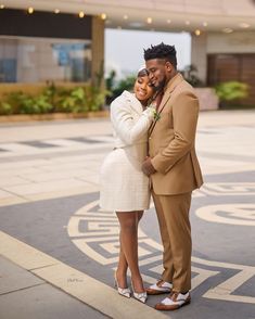 a man and woman standing next to each other in front of a building