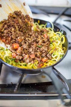 a skillet filled with meat and noodles on top of a stove