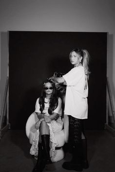 two women are sitting in chairs and one is getting her hair done