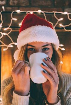 a woman in a santa hat drinking from a mug