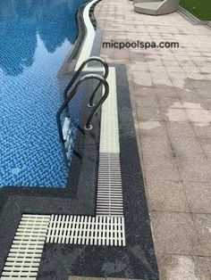 an empty swimming pool in the middle of a tiled area with steps leading up to it