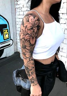 a woman with a flower tattoo on her arm and shoulder is walking down the street