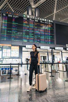 a woman standing in an airport with her luggage