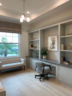 a home office with built - in shelving, desk and chair by the window