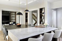 a large kitchen with marble counter tops and white chairs