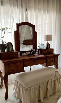 a bed sitting under a mirror next to a wooden desk with a bench underneath it