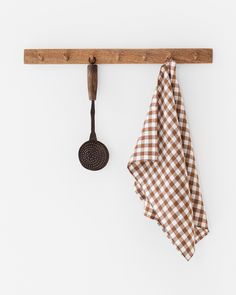 a brown and white checkered towel hanging on a wooden rack with a frying pan