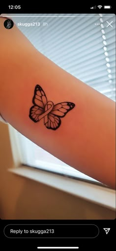 a small butterfly tattoo on the left arm and right arm is black with white outline