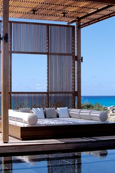 a couch sitting under a wooden structure next to the ocean