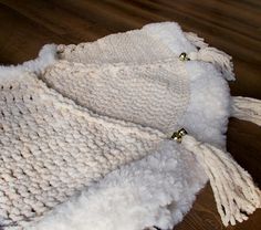 two white knitted hats laying on top of a wooden floor