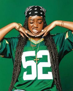 a woman with dreadlocks and a green jersey is holding her hands on her head