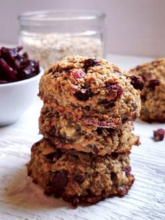 three oatmeal cookies stacked on top of each other with cranberries in the background