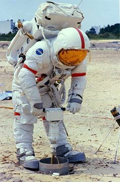 an astronaut standing on the ground next to a small object