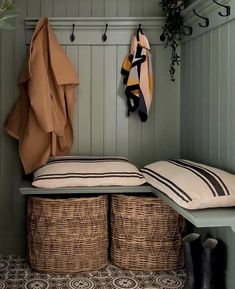 a bench with two baskets underneath it and coat hooks on the back wall above them