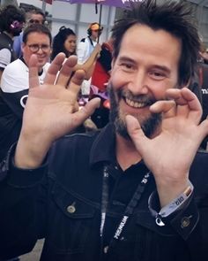 a man is smiling while holding his hands up in front of him and posing for the camera