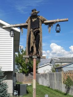 a scarecrow standing on top of a wooden pole