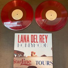 two red vinyl records sitting on top of a table