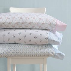 a stack of pillows sitting on top of a white chair next to a blue wall