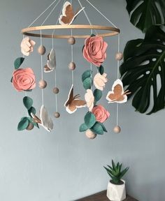 a mobile with flowers and hearts hanging from it's sides on a table next to a potted plant