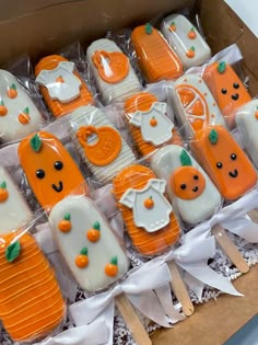 a box filled with lots of orange and white decorated cookies on top of paper towels