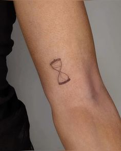 a woman's arm with a tattoo on it that has an hourglass in the sand