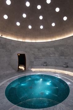 an indoor swimming pool surrounded by circular lights and concrete walls with round holes in the ceiling